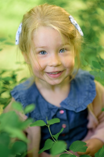 Une petite fille de 3 ans se promène dans le parc vêtue d'une robe et d'un pull rose