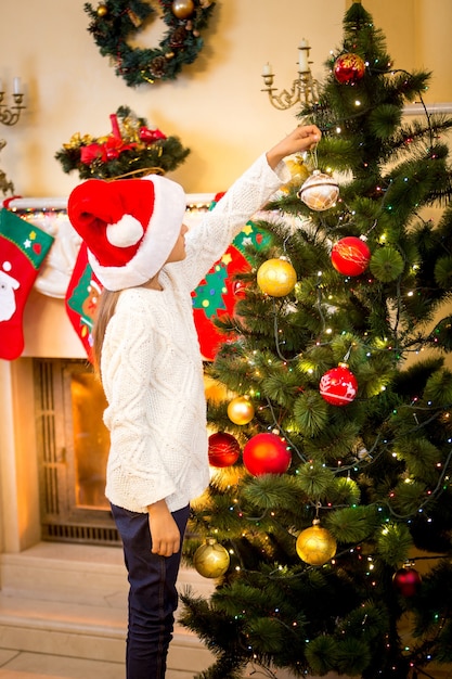 Petite fille accrochant la boule décorative sur l'arbre de Noël