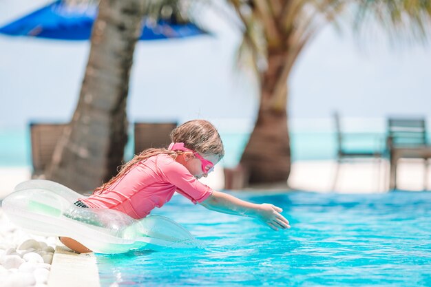 Petite fille adorable active dans la piscine extérieure prête à nager