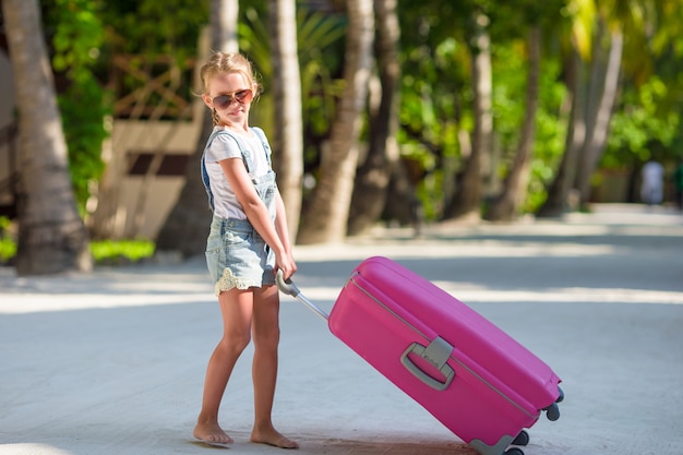 Petite fille adorable avec de gros bagages pendant les vacances d'été