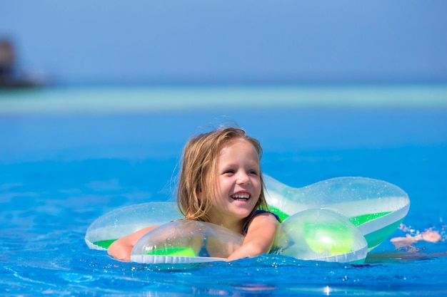 Petite fille adorable heureuse dans la piscine extérieure