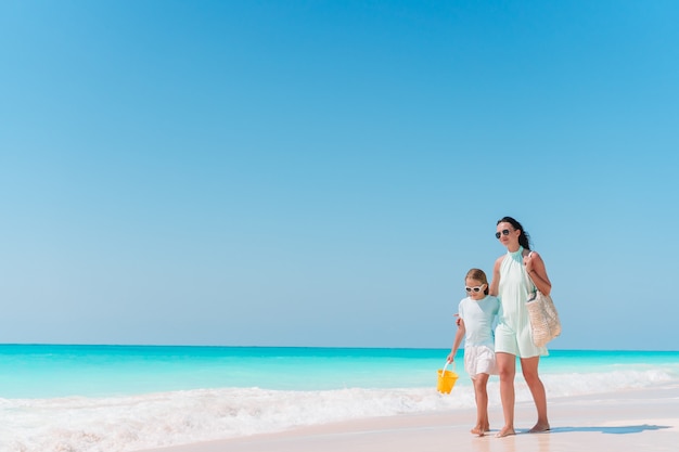 Petite fille adorable et jeune maman sur une plage tropicale