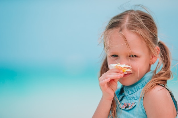 Petite fille adorable, sentant les fleurs colorées au jour d'été