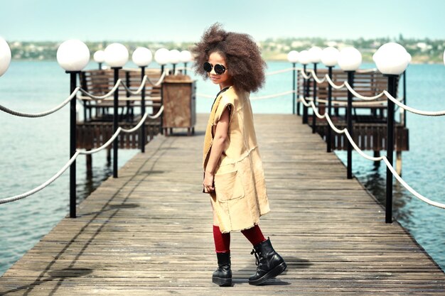 Photo petite fille afro-américaine portant des vêtements élégants à l'extérieur. concept de mode enfant