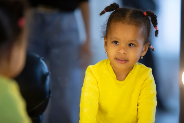 Une petite fille afro-américaine regarde son reflet dans le miroir.