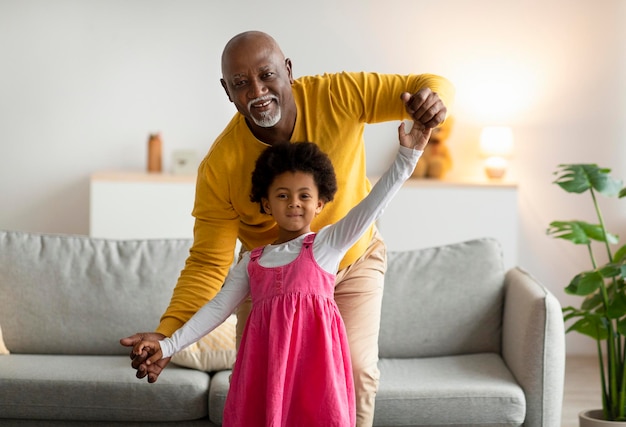 Petite fille afro-américaine souriante et vieil homme dansant et s'amusant