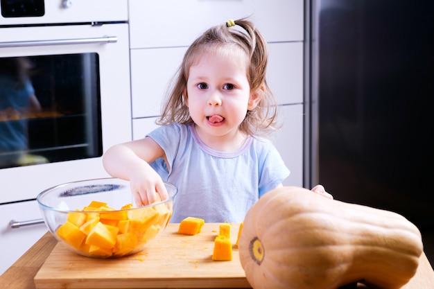 Petite fille aidant sa mère à préparer une citrouille