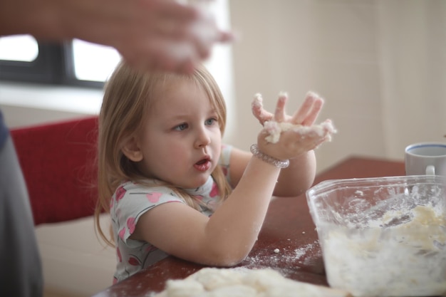 Petite fille aide à cuisiner en pétrissant la pâte un enfant aide à cuisiner à la maison Nourriture maison et petite aide