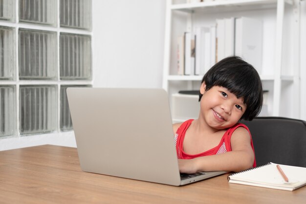 Petite fille à l'aide d'un ordinateur portable à une table