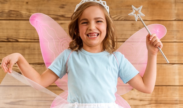 Petite fille avec des ailes et une baguette magique.