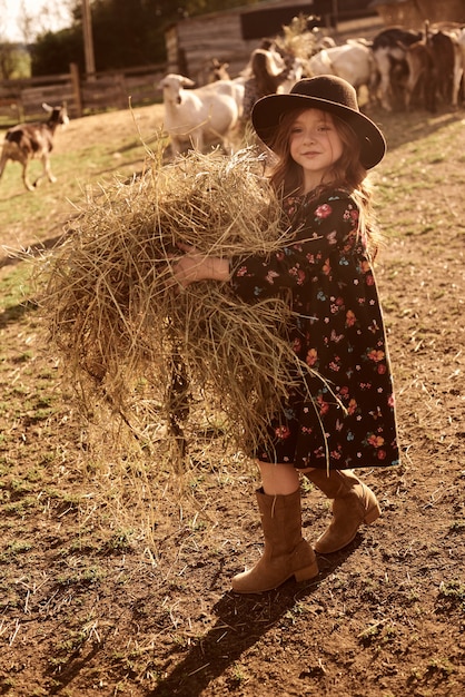 Une petite fille aime être dans une ferme avec des animaux.