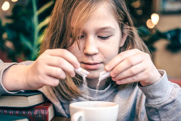 Une petite fille ajoute du sucre à son thé