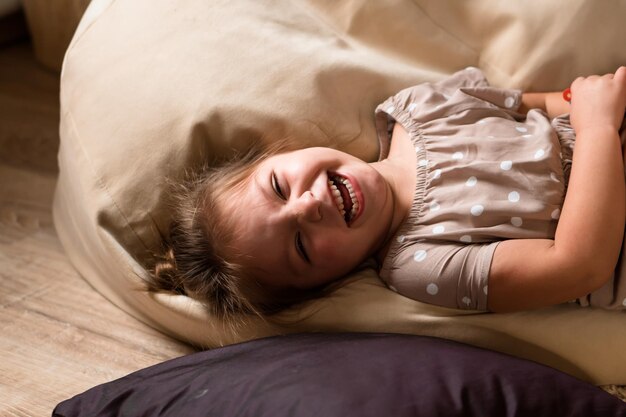 Petite fille allongée sur un canapé à la maison et riant