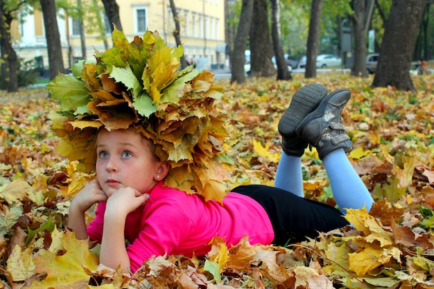 Petite fille allongée sur les feuilles jaunes du parc