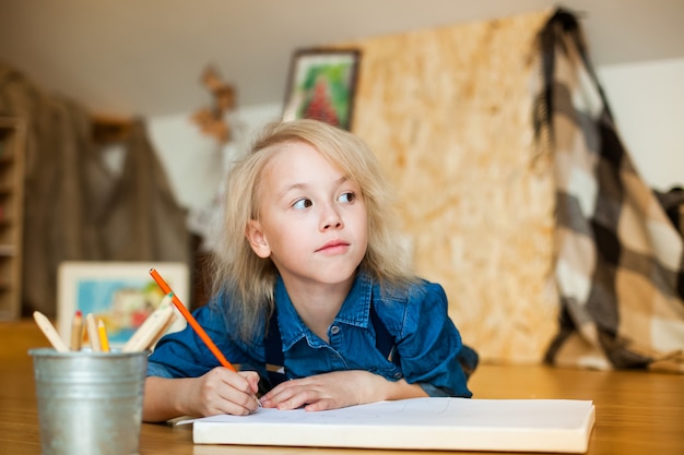 Petite fille allongée sur le sol et dessin aux crayons de couleur