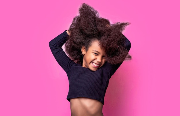 Petite fille américaine souriante Fille souriante et cheveux bouclés Rire mignon portrait de fille afro mignon petite fille multiraciale souriante isolée sur un fond rose