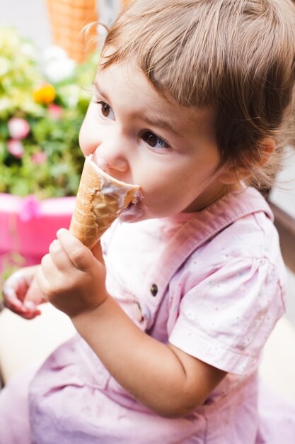 La petite fille amoureuse mange une glace au café en plein air