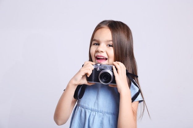 Petite fille avec appareil photo vintage sur fond clair