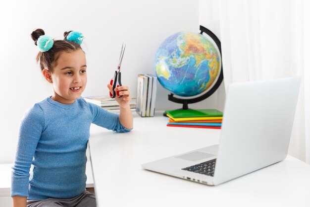 petite fille apprenant la coupe de cheveux sur un ordinateur portable en ligne