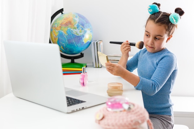 petite fille apprenant le maquillage sur ordinateur portable en ligne, apprentissage à distance