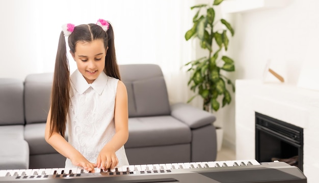 Photo une petite fille apprend à jouer du synthétiseur. apprendre à jouer des instruments de musique.