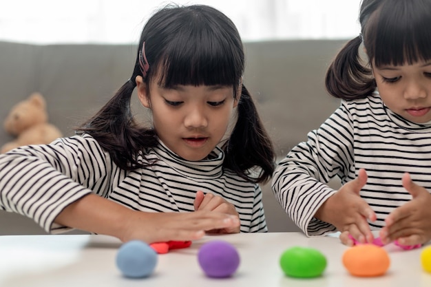 La petite fille apprend à utiliser de la pâte à modeler colorée dans une pièce bien éclairée