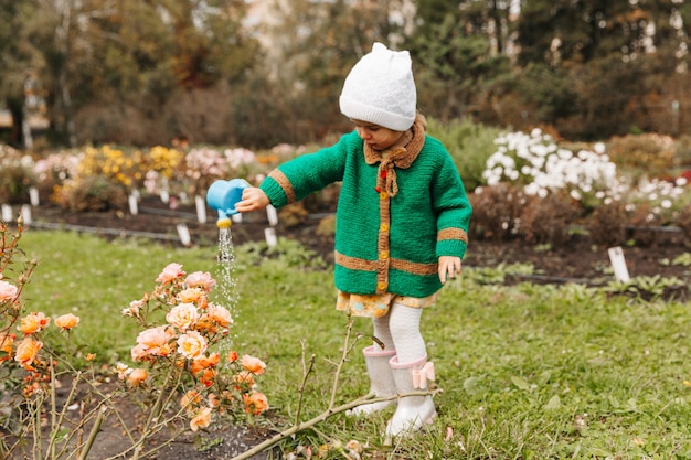 Petite fille arrosant des fleurs avec un arrosoir dans le jardin
