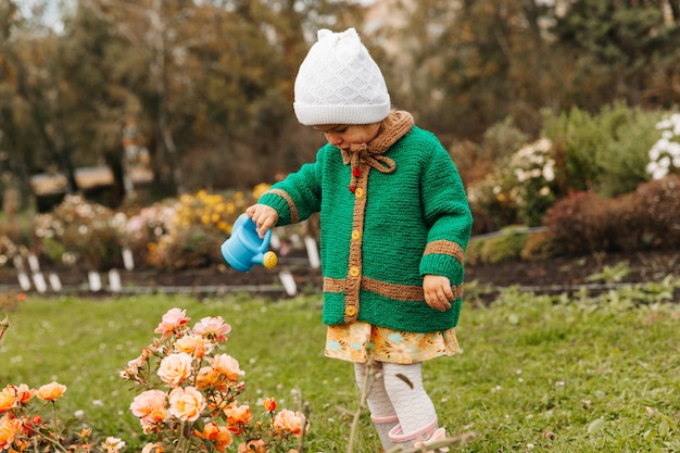 Petite fille arrosant des fleurs avec un arrosoir dans le jardin