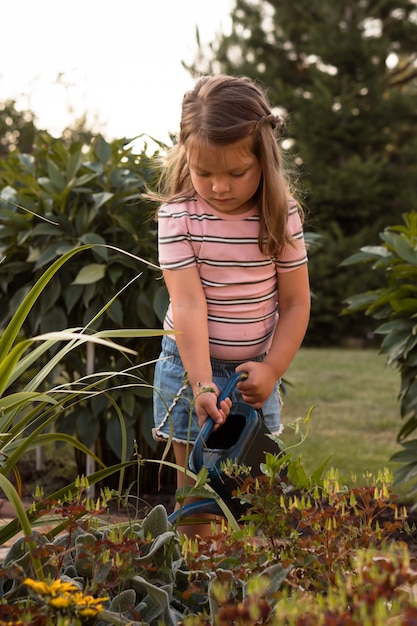 Petite fille arrosant les plantes dans le jardin en été à la campagne