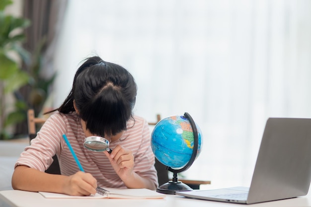 Une petite fille asiatique apprend le concept de modèle de globe pour sauver le monde et apprendre par le jeu pour l'éducation des enfants à la maison