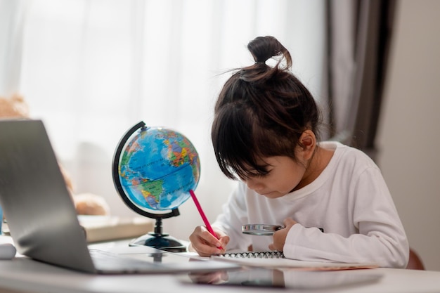 Une petite fille asiatique apprend le concept de modèle de globe pour sauver le monde et apprendre par le jeu pour l'éducation des enfants à la maison