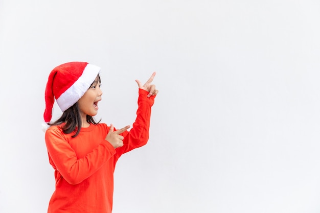 Petite fille asiatique en bonnet de Noel rouge sur fond blanc.