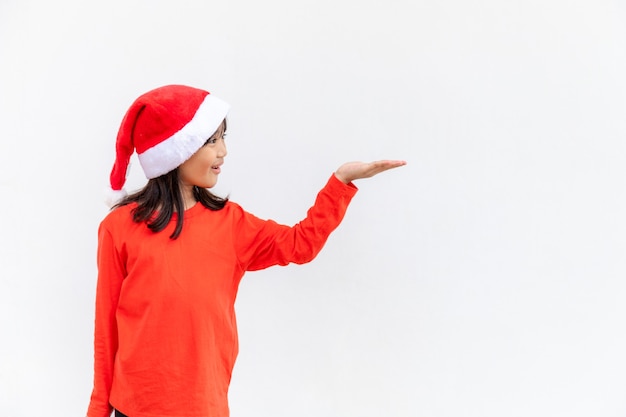 Petite fille asiatique en bonnet de Noel rouge sur fond blanc.