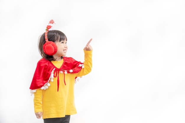 Petite fille asiatique en bonnet de Noel rouge sur fond blanc.