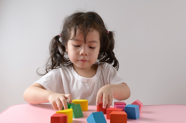 Petite fille asiatique bouclée aime jouer au jouet à la maison. Concept de l'éducation.