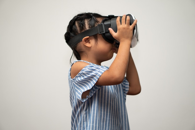 La petite fille asiatique avec un casque de réalité virtuelle est passionnante pour une nouvelle expérience.