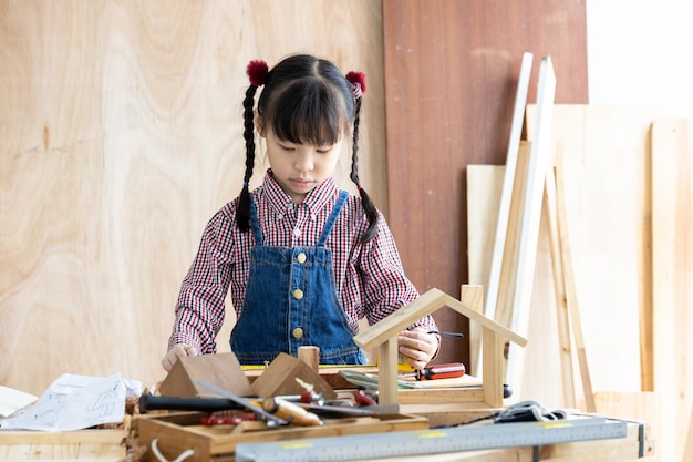 Petite fille asiatique charpentier travaillant sur le travail du bois dans un atelier de menuiserie Charpentier travaillant sur l'artisanat du bois à l'atelier matériaux de construction meubles en bois Petite fille asiatique travaille dans un atelier de menuiserie