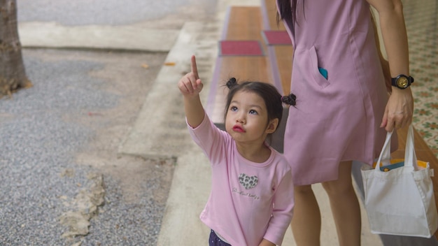 Petite fille asiatique courant et marchant sur le champ d'herbe