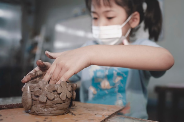 Petite fille asiatique créant un bol d'argile de potier à la maisonÉducationhobby et concept d'artisanat