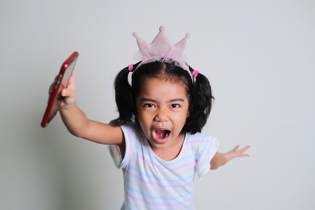 Photo petite fille asiatique criant en courant vers l'avant avec sa main tenant un téléphone portable