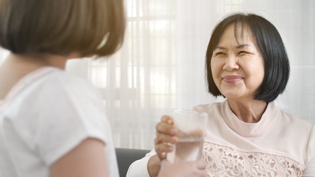 Photo petite fille asiatique donne un verre d'eau à sa grand-mère