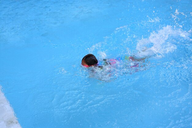 Petite fille asiatique enfant apprenant à nager dans la piscine. Écolière pratiquant à la natation.