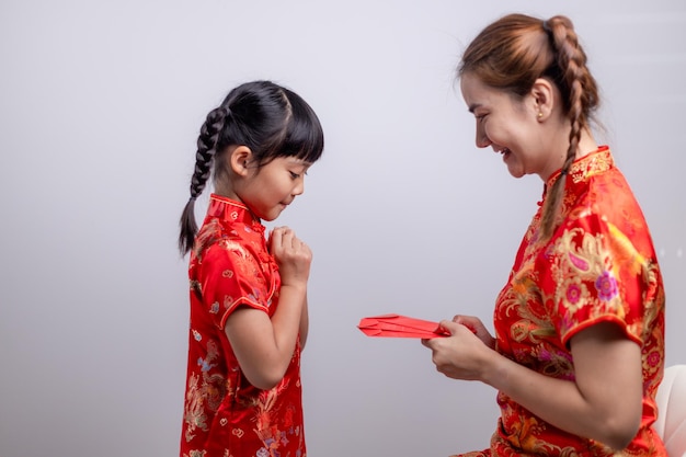 Une petite fille asiatique heureuse a reçu une enveloppe rouge de sa mère pour le nouvel an chinois