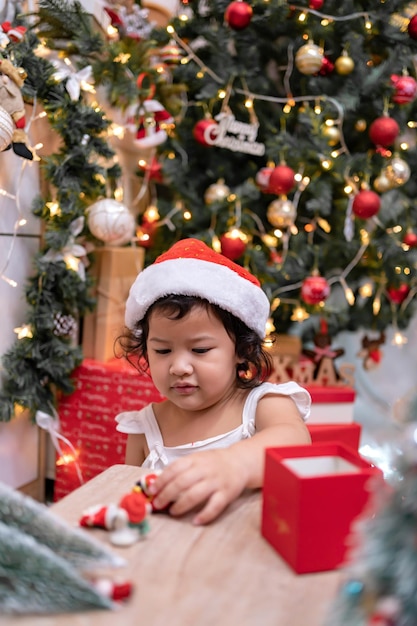 Une petite fille asiatique heureuse s'amuse le jour de Noël. Enfant avec parent avec décoration d'arbre de Noël à la maison en vacances.