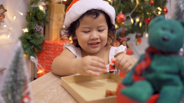 Une petite fille asiatique heureuse s'amuse le jour de Noël. Enfant avec parent avec décoration d'arbre de Noël à la maison en vacances.