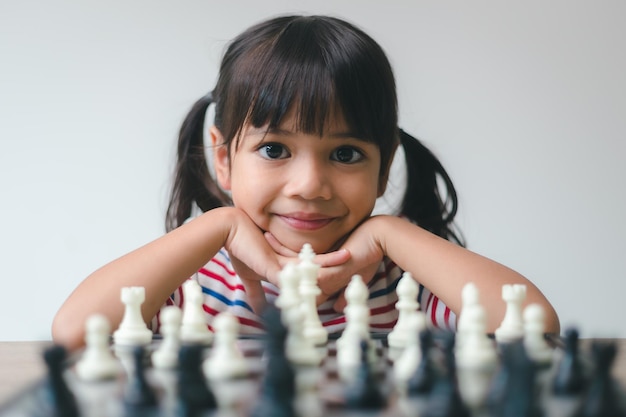 Petite fille asiatique jouant aux échecs à la maison un jeu d'échecs