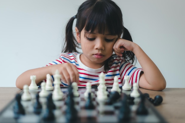 Petite fille asiatique jouant aux échecs à la maison un jeu d'échecs