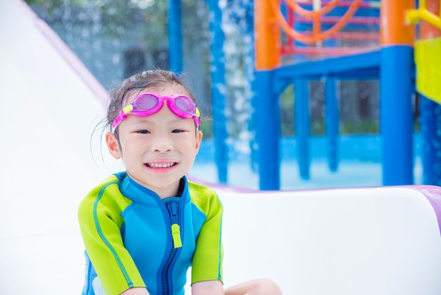 Petite fille asiatique jouant et sourit au parc aquatique