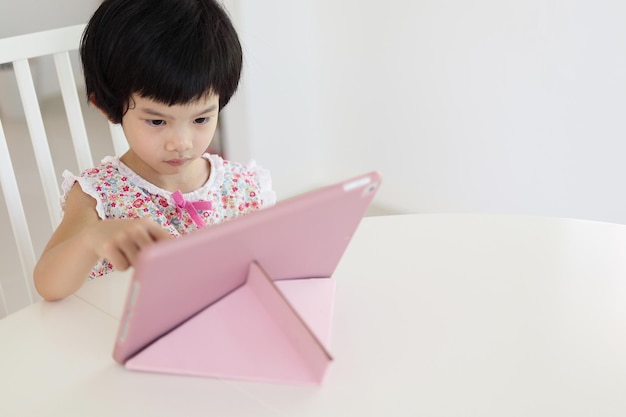 Petite fille asiatique jouant à la tablette numérique à la maison