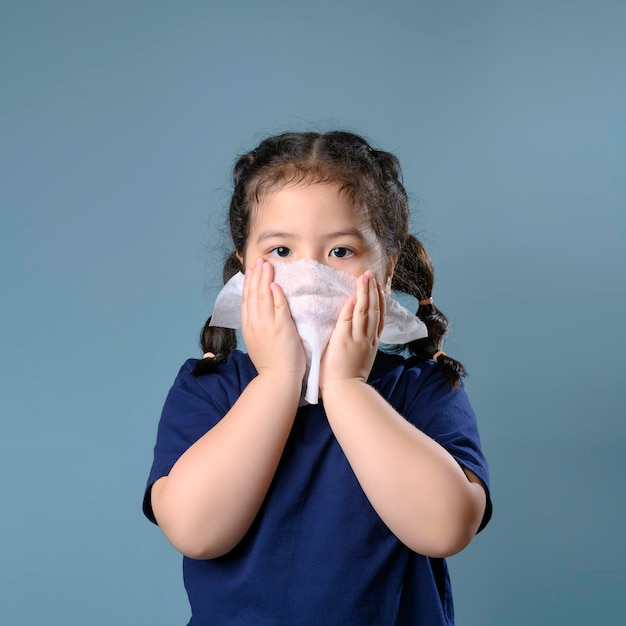 Petite fille asiatique malade et triste avec des éternuements sur le nez et une toux froide sur du papier de soie parce que faible ou virus et bactéries dus à la poussière et à l'école maternelle et maternelle pour la médecine.